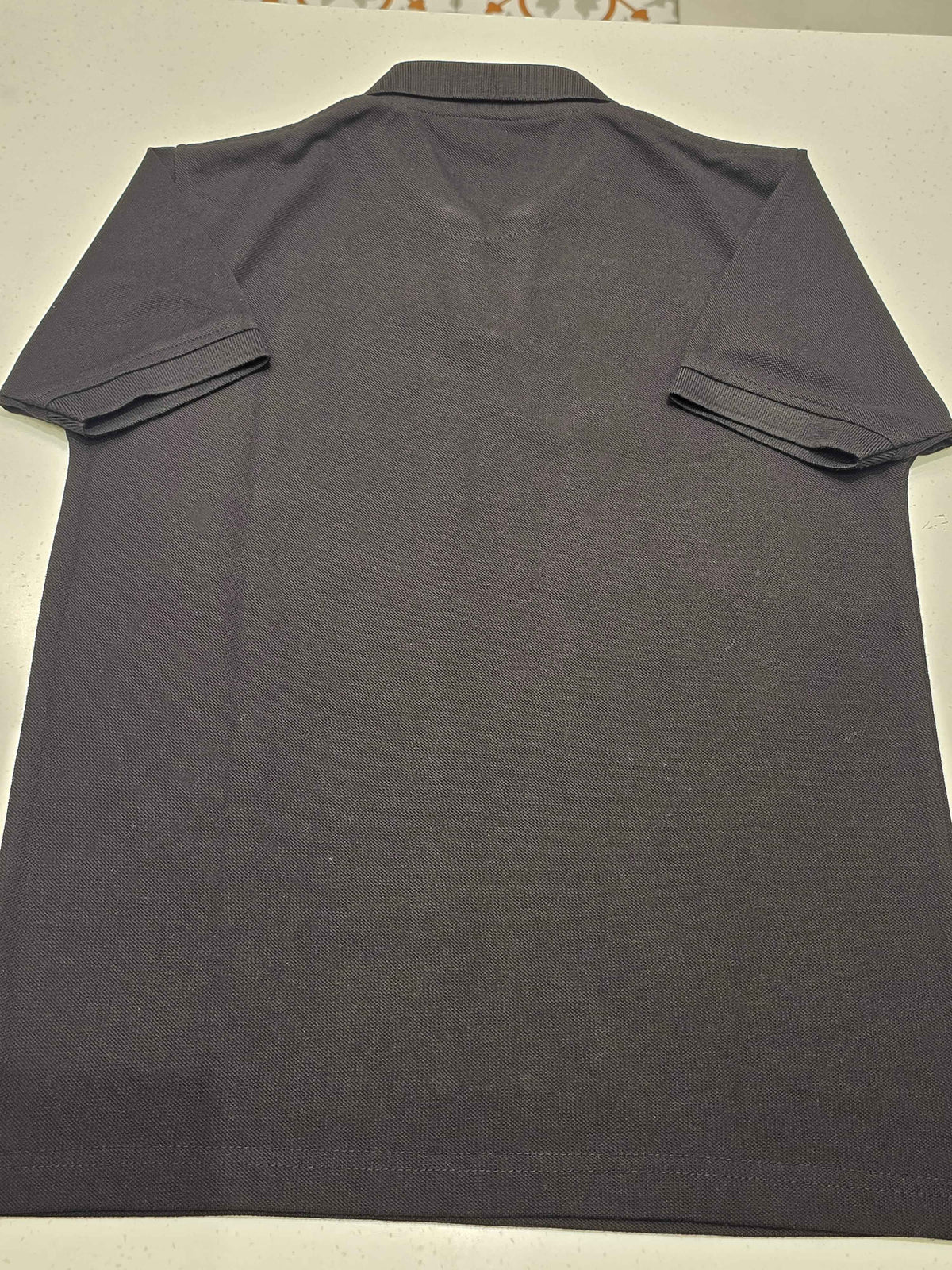 black or dark charcoal knit polo shirt featuring a red contrast inner placket and an embroidered chest logo