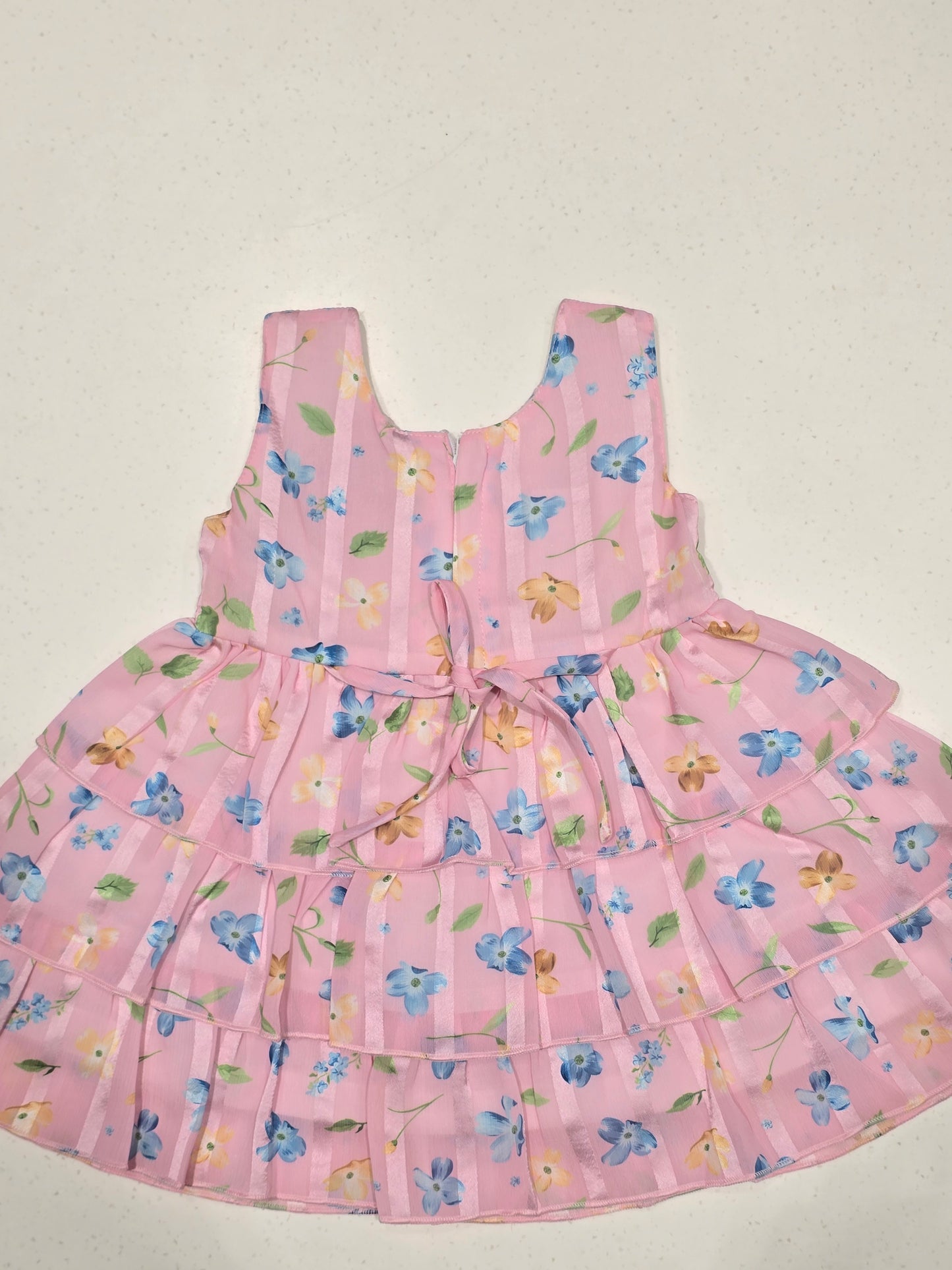 pink tiered floral frock dress for baby girls, featuring a smocked bodice and an accenting blue bow belt