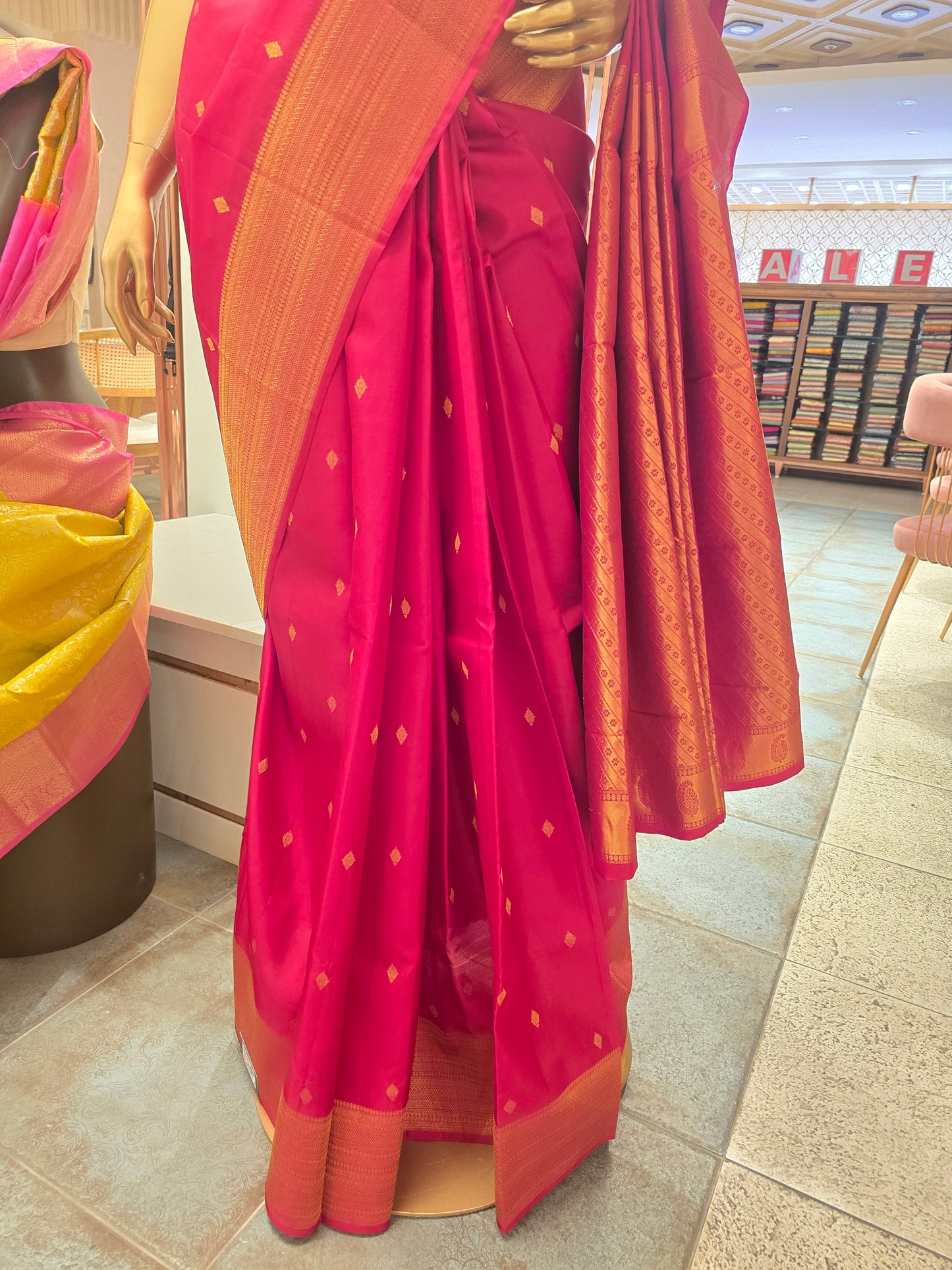 Rani pink silk saree adorned with a traditional golden zari border and small geometric butta motifs woven throughout the body
