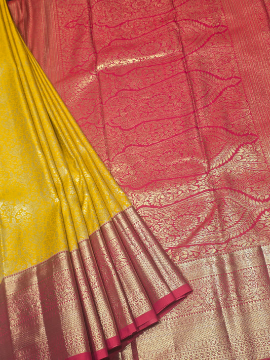yellow and pink Kanchipuram style semi-silk saree adorned with elegant zari floral patterns and a broad contrast border.