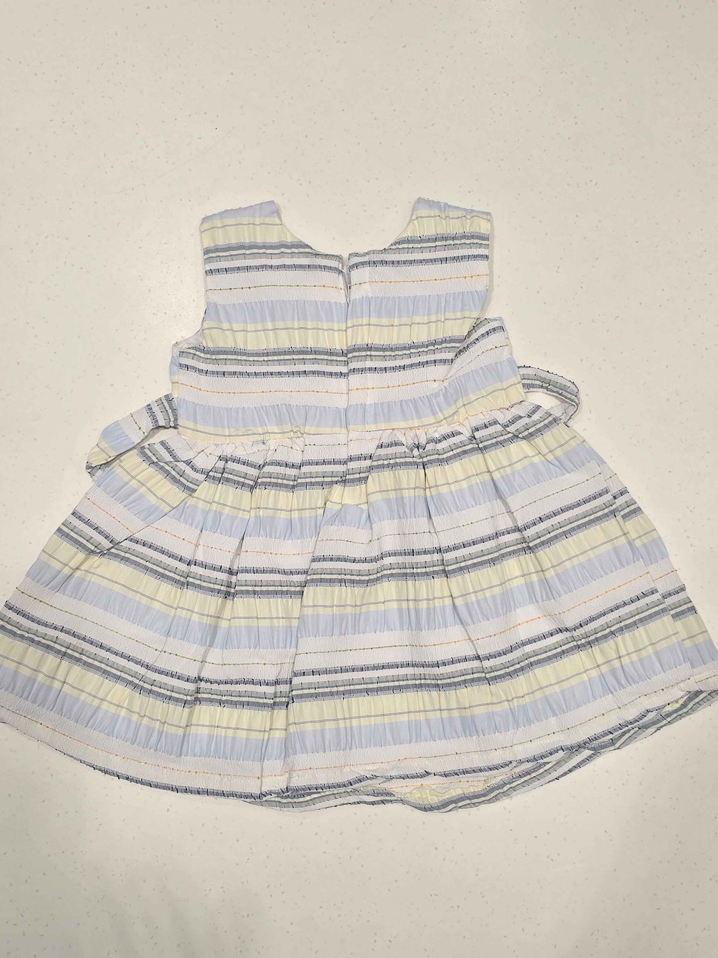 Bodice: Features an upper sleeveless cut with a rounded neckline, structured horizontal paneling, and an embroidered text patch detail on the upper left chest.