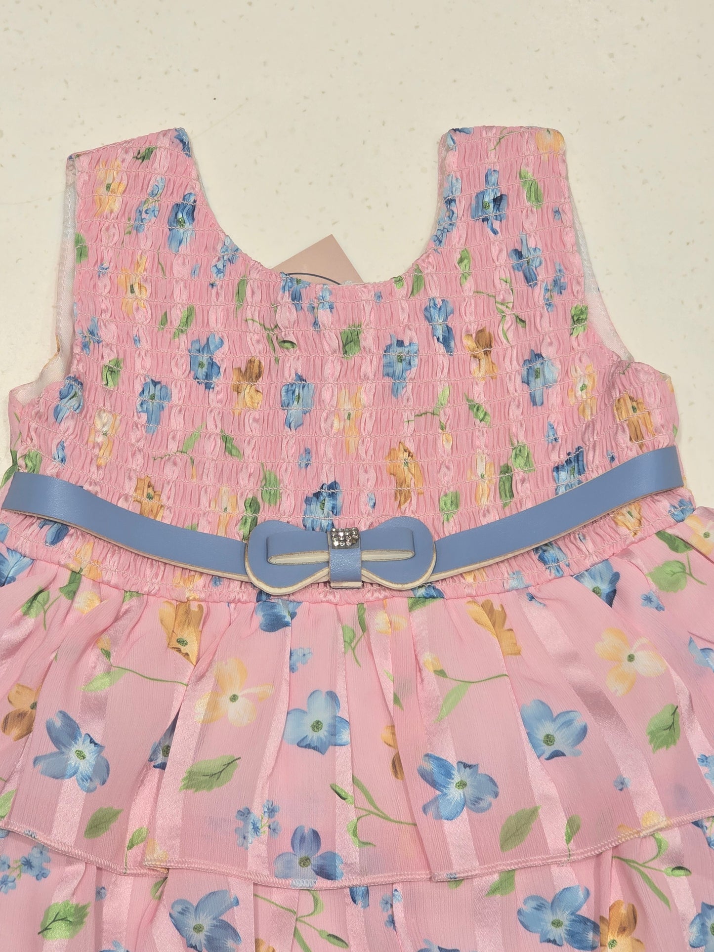 pink tiered floral frock dress for baby girls, featuring a smocked bodice and an accenting blue bow belt