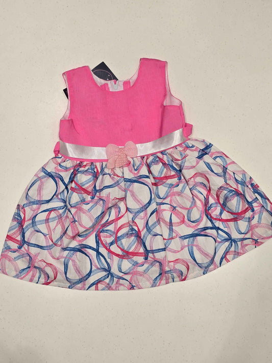 sleeveless cotton baby frock features a bright pink bodice paired with a contrasting white skirt decorated with abstract swirls. A light pink polka-dot bow accent highlights the satin-like ribbon waistband,