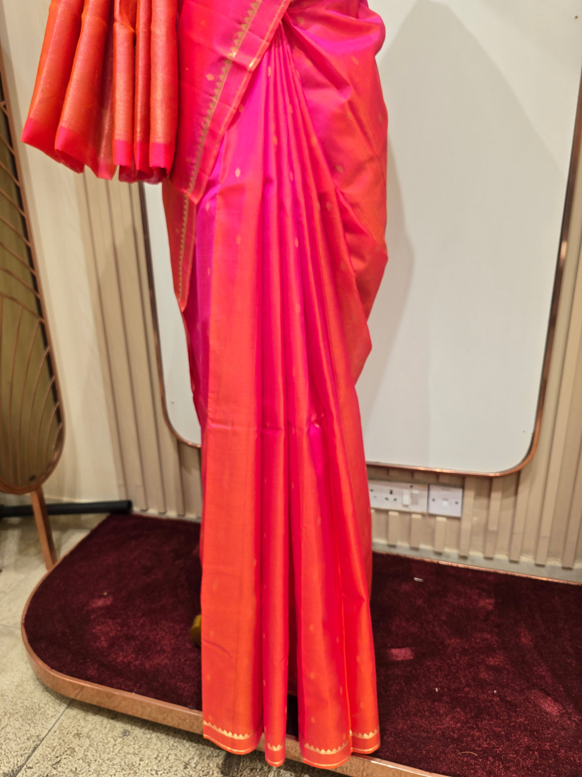 vibrant dual-tone pink and orange Kanchipuram silk saree elegantly draped on a mannequin.