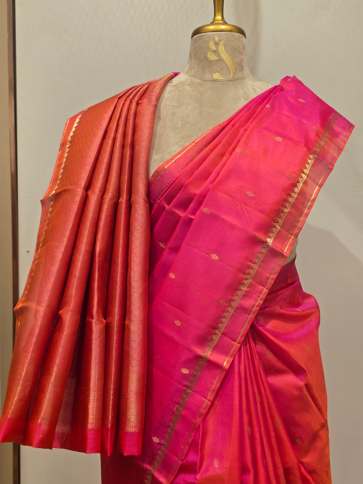vibrant dual-tone pink and orange Kanchipuram silk saree elegantly draped on a mannequin.