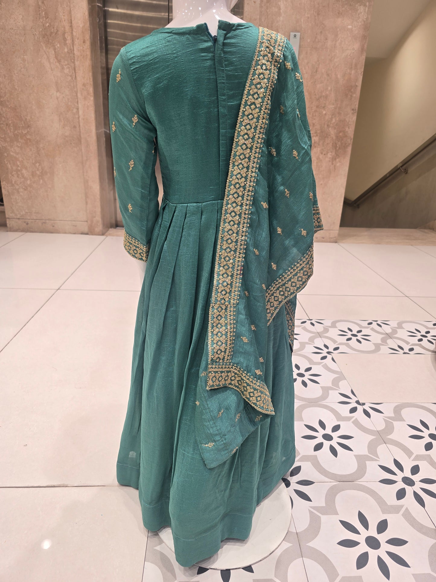 Rama green or teal-toned silk pleated Anarkali gown styled with an intricately embroidered bodice and a matching border dupatta.
