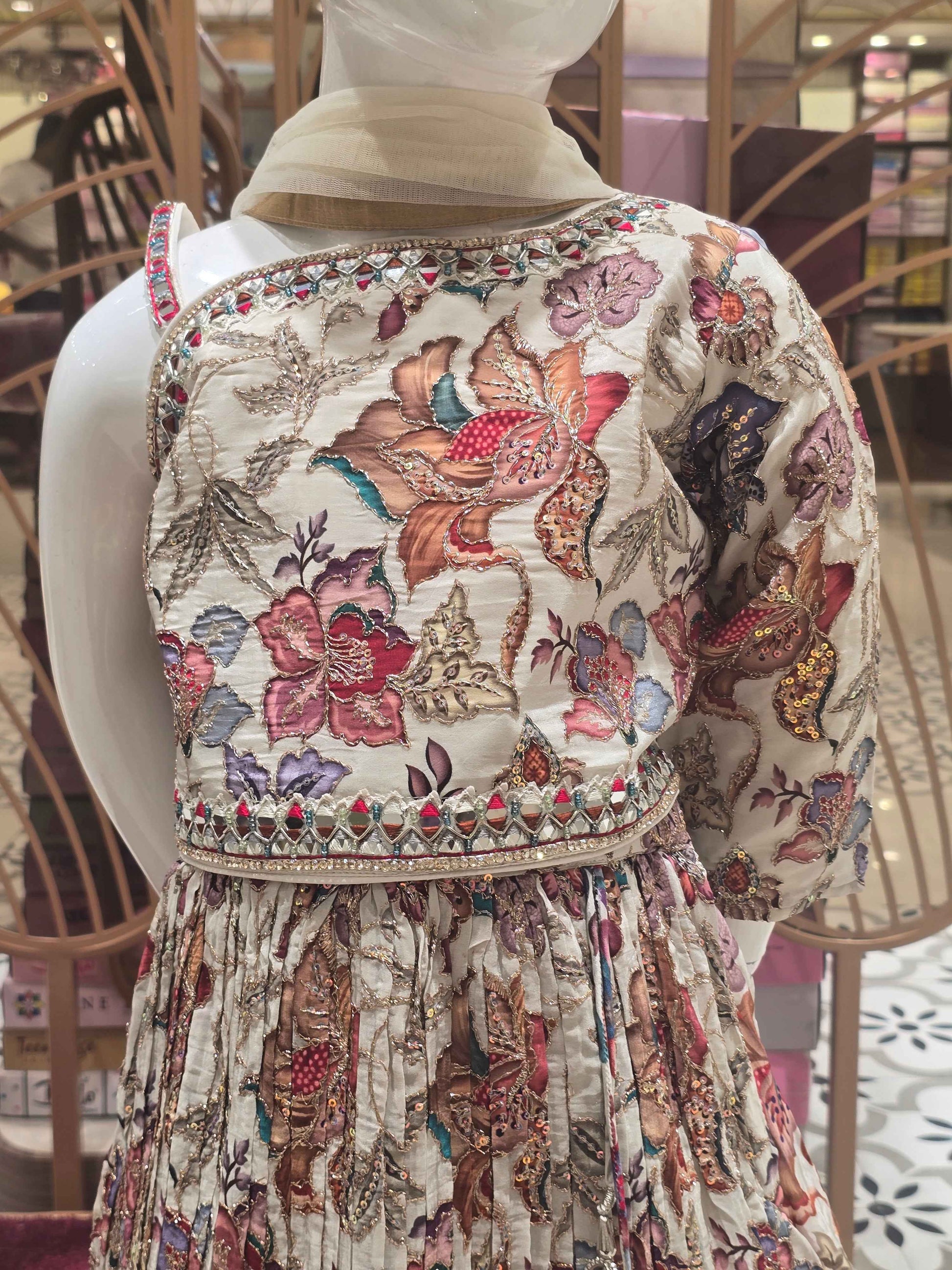 Crepe material cream based gaghra with printed floral & zari work over the body. Right shoulder with speghetti left had full sleeves