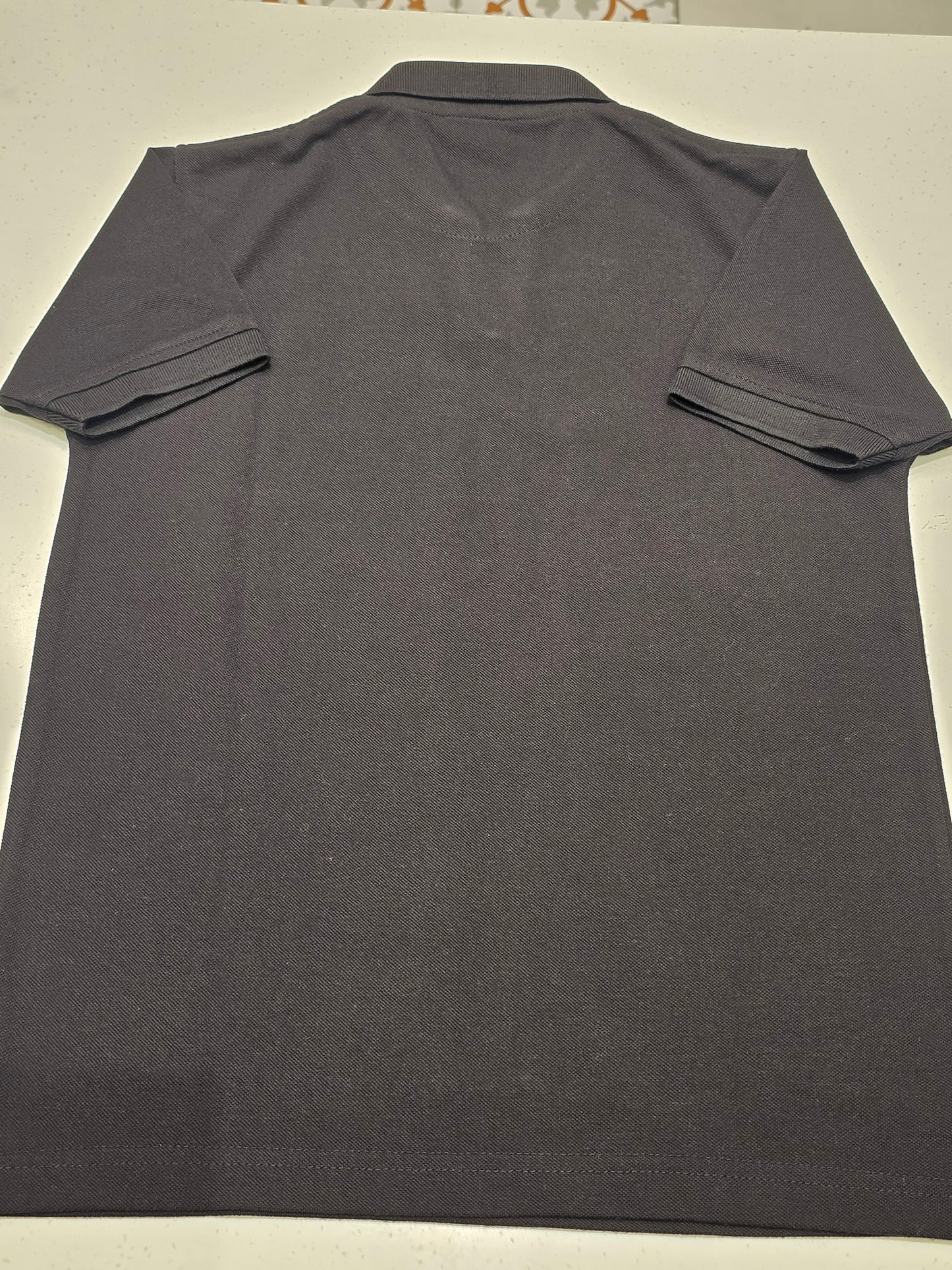 black or dark charcoal knit polo shirt featuring a red contrast inner placket and an embroidered chest logo