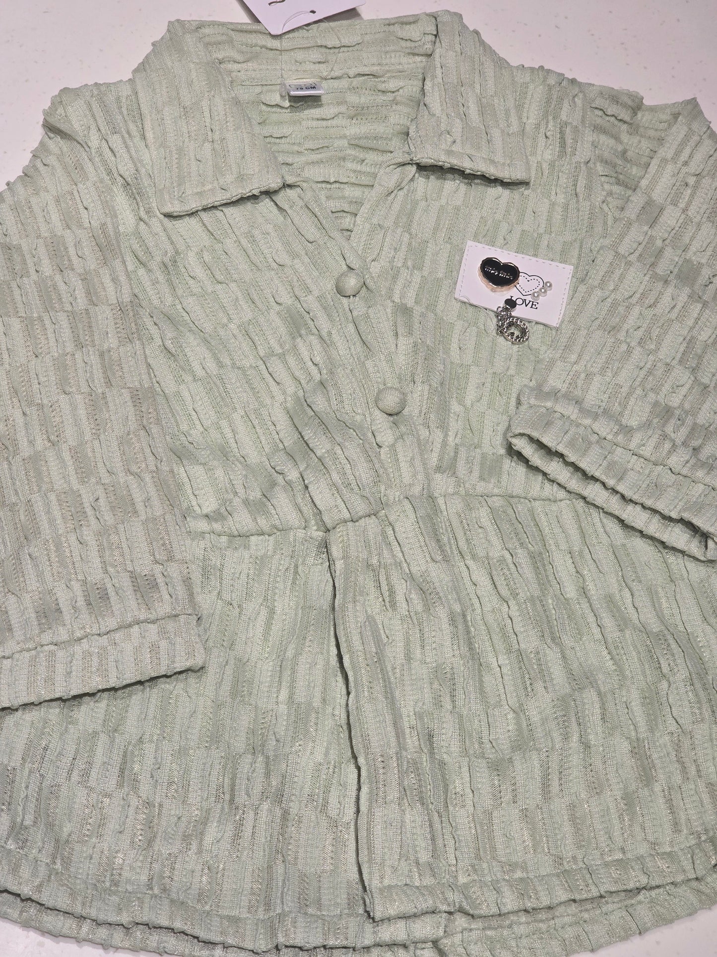 light sage green textured top/cardigan featuring a distinctive puckered or "popcorn" brick-weave pattern
