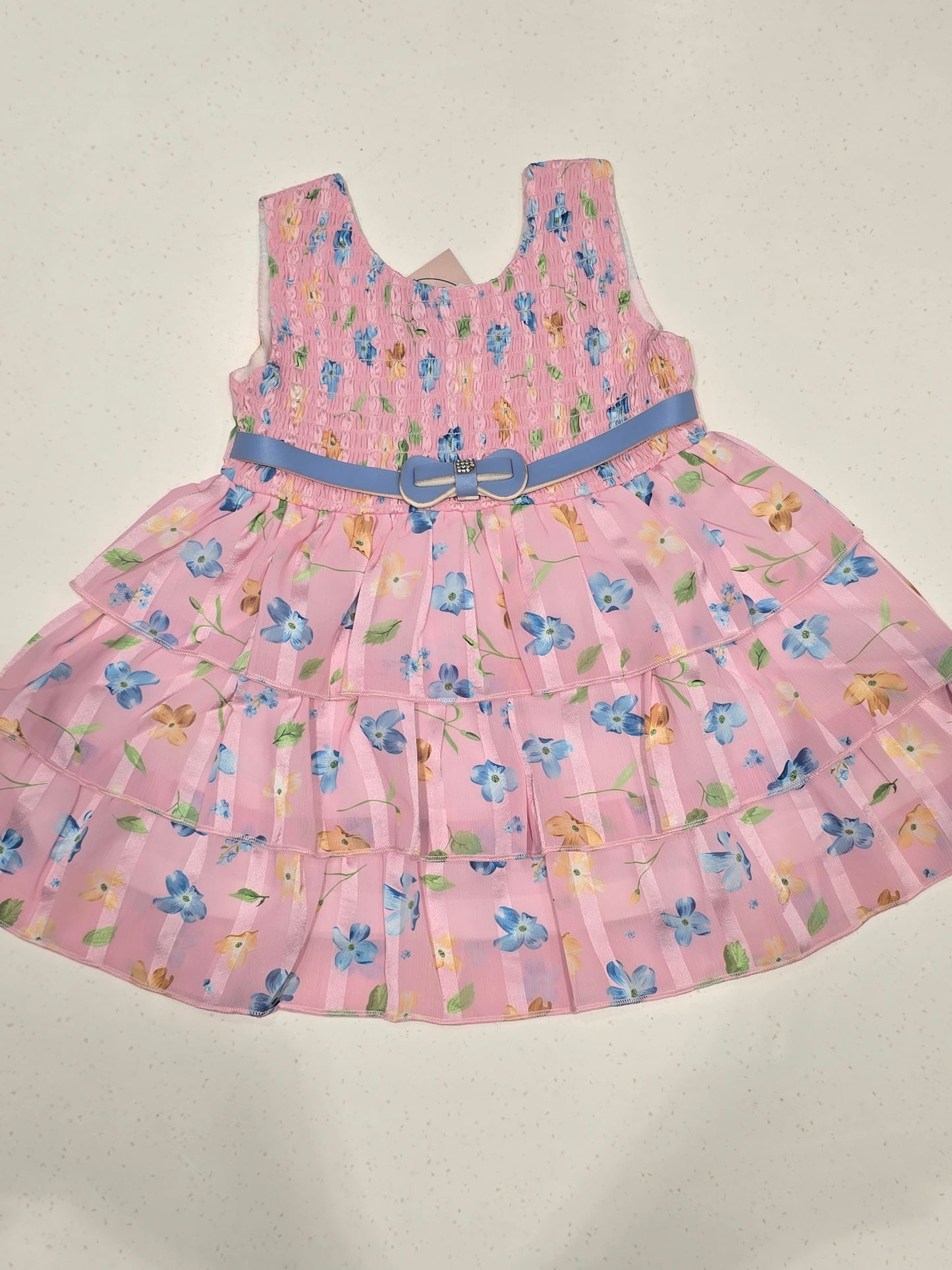 pink tiered floral frock dress for baby girls, featuring a smocked bodice and an accenting blue bow belt