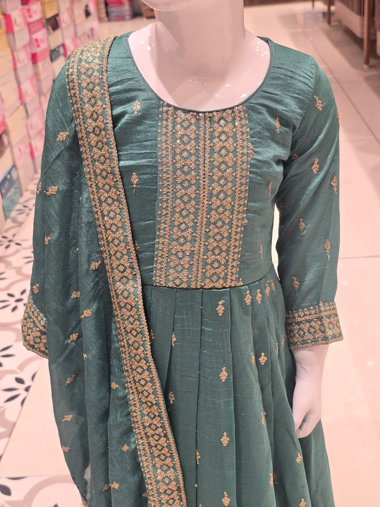 Rama green or teal-toned silk pleated Anarkali gown styled with an intricately embroidered bodice and a matching border dupatta.