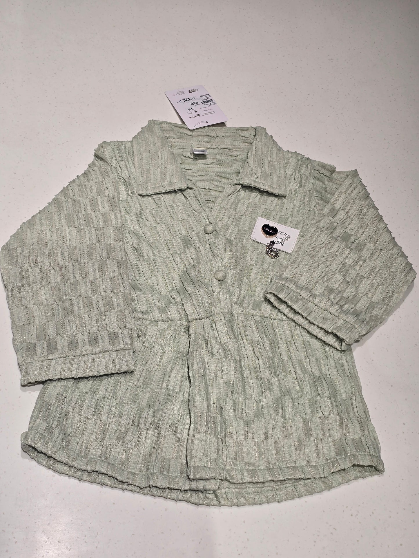light sage green textured top/cardigan featuring a distinctive puckered or "popcorn" brick-weave pattern