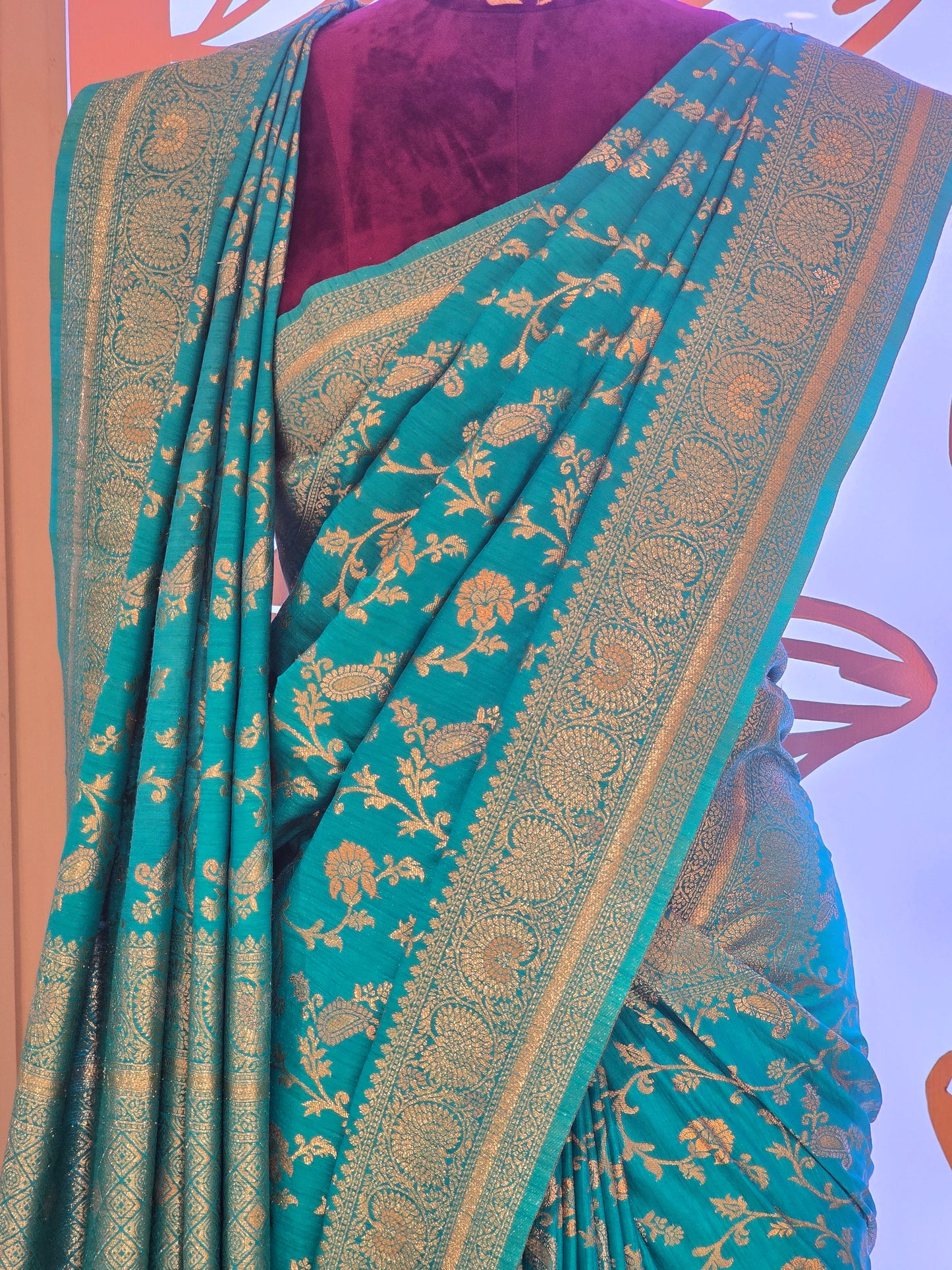 traditional turquoise Banarasi silk saree featuring intricate gold zari floral vines and a broad,