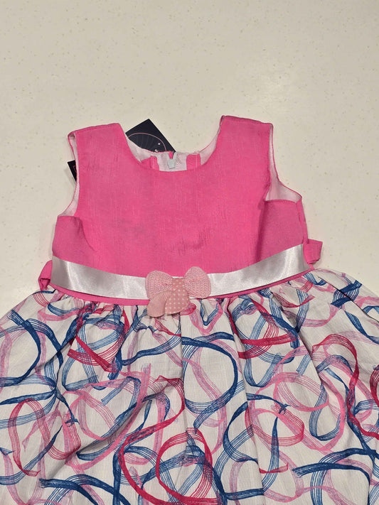 sleeveless cotton baby frock features a bright pink bodice paired with a contrasting white skirt decorated with abstract swirls. A light pink polka-dot bow accent highlights the satin-like ribbon waistband,
