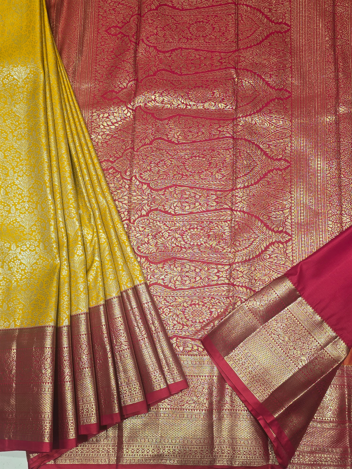 yellow and pink Kanchipuram style semi-silk saree adorned with elegant zari floral patterns and a broad contrast border.