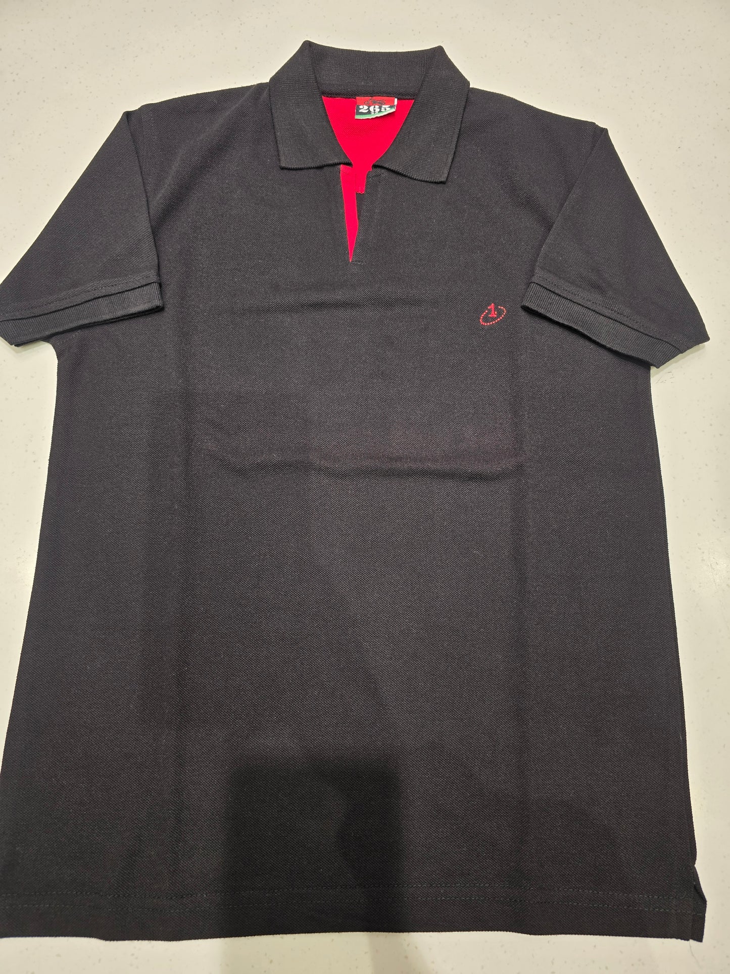 black or dark charcoal knit polo shirt featuring a red contrast inner placket and an embroidered chest logo