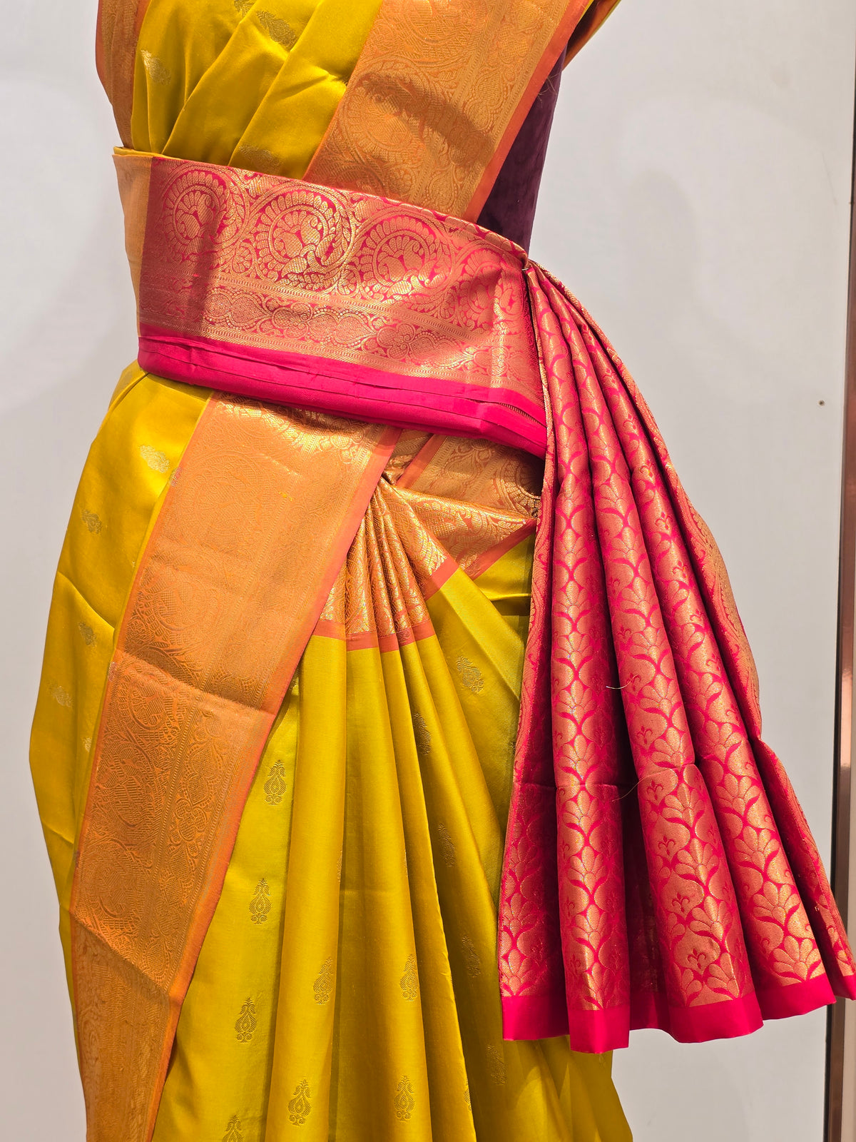 pure Kanjivaram silk saree rendered in a vibrant mustard yellow and contrasting rani pink color scheme.