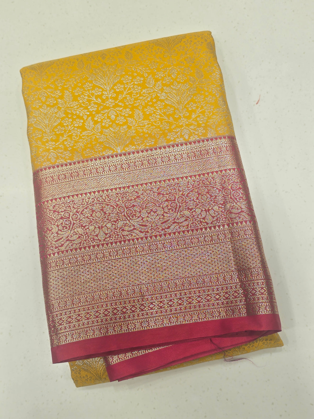 yellow and pink Kanchipuram style semi-silk saree adorned with elegant zari floral patterns and a broad contrast border.