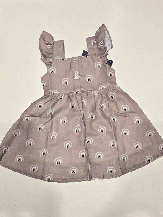 baby girl’s sleeveless cotton frock featuring a flared skirt, a gathered waist, square neckline, shoulder flutter ruffles, and a button-down back closure. It
