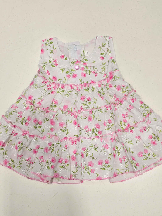 white baby girl's cotton frock dress featuring a vibrant pink floral print distributed in distinct tiered ruffle layers.