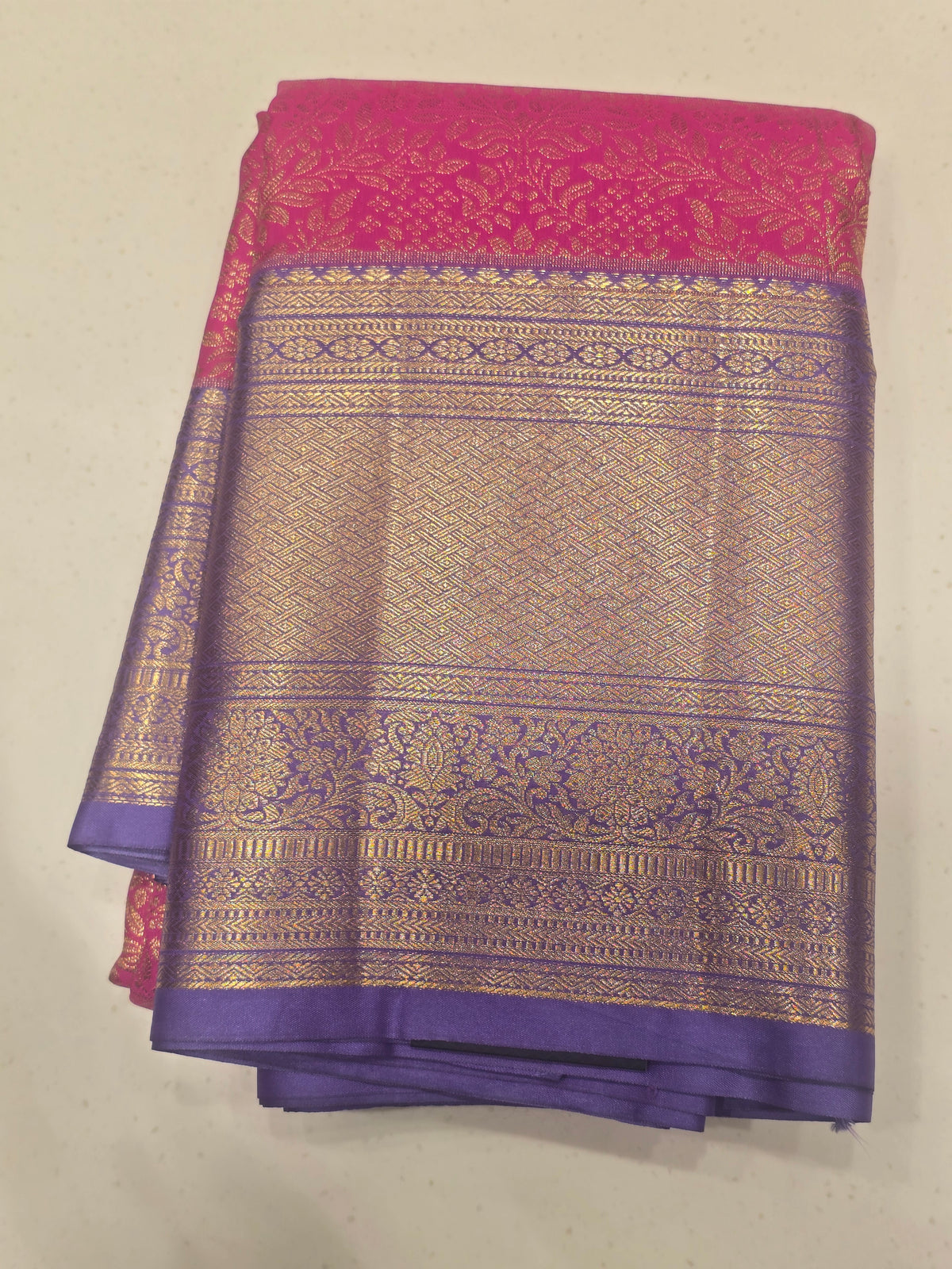 semi silk saree featuring a vibrant magenta body accented by a deep violet or purple contrast border.